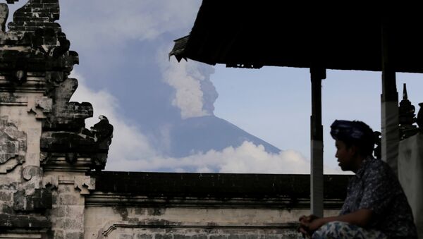 A Balinese man sits as Mount Agung volcano erupts at Lempuyang Temple in Karangasem, Bali, Indonesia November 27, 2017 - Sputnik International