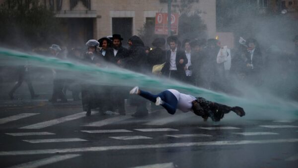 A bystander falls as Israeli police spray water during a demonstration by ultra-Orthodox Jews against the detention of members of their community who failed to report to a military recruiting office, in Jerusalem November 26, 2017 - Sputnik International