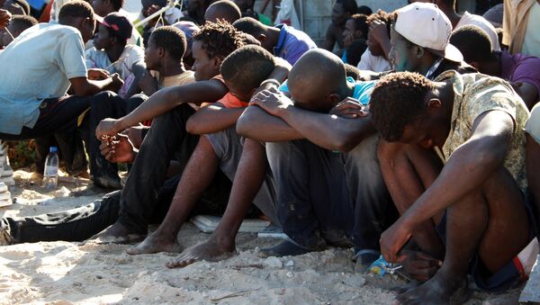 Illegal migrants from sub-Saharan Africa rest after they were rescued by the Libyan coast guard when their boat sank off the coastal town of Guarabouli, 60 km (36 miles) east of the capital Tripoli on October 2, 2014 - Sputnik International