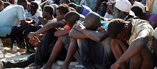 Illegal migrants from sub-Saharan Africa rest after they were rescued by the Libyan coast guard when their boat sank off the coastal town of Guarabouli, 60 km (36 miles) east of the capital Tripoli on October 2, 2014 - Sputnik International