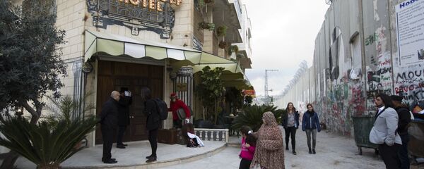 People pass by the The Walled Off Hotel and the Israeli security barrier in the West Bank city of Bethlehem People pass by the The Walled Off Hotel and the Israeli security barrier in the West Bank city of Bethlehem - Sputnik International