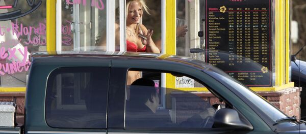 In this Feb. 2, 2010, file photo, a barista at a Grab-N-Go Bikini Hut espresso stand holds money as she waves to a customer, just outside the city limits of Everett, Wash., in Snohomish County. Seven bikini baristas and the owner of a chain of the coffee stands called Hillbilly Hotties sued the city of Everett, Washington, on Monday, Sept. 11, 2017, saying two recently passed ordinances banning bare skin violate their right to free expression. In this Feb. 2, 2010, file photo, a barista at a Grab-N-Go Bikini Hut espresso stand holds money as she waves to a customer, just outside the city limits of Everett, Wash., in Snohomish County. Seven bikini baristas and the owner of a chain of the coffee stands called Hillbilly Hotties sued the city of Everett, Washington, on Monday, Sept. 11, 2017, saying two recently passed ordinances banning bare skin violate their right to free expression. - Sputnik International