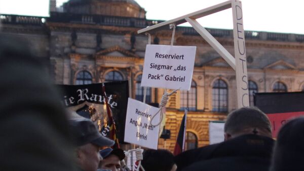 In this Oct. 12, 2015 photo a demonstrator carries a mock gallows with two hangman's nooses, marked Reserved for Angela Merkel and Reserved for Sigmar Gabriel, her deputy, during a demonstration of PEGIDA (Patriotic Europeans against the Islamization of the West) in Dresden, Germany - Sputnik International