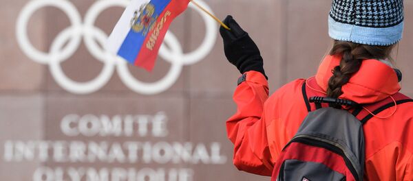 A supporter waves a Russian flag in front of the logo of the International Olympic Committee (IOC) at their headquarters on December 5, 2017 in Pully near Lausanne - Sputnik International