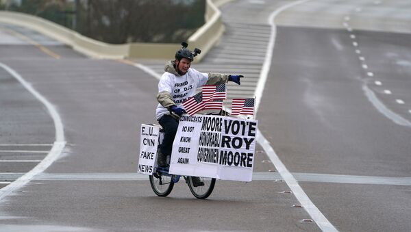 A man rides his bike with signs of support for Alabama Republican senatorial candidate Roy Moore around a venue that will host U.S. President Donald Trump later in the day in Pensacola, Florida, U.S., December 8, 2017 - Sputnik International