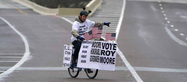 A man rides his bike with signs of support for Alabama Republican senatorial candidate Roy Moore around a venue that will host U.S. President Donald Trump later in the day in Pensacola, Florida, U.S., December 8, 2017 A man rides his bike with signs of support for Alabama Republican senatorial candidate Roy Moore around a venue that will host U.S. President Donald Trump later in the day in Pensacola, Florida, U.S., December 8, 2017 - Sputnik International