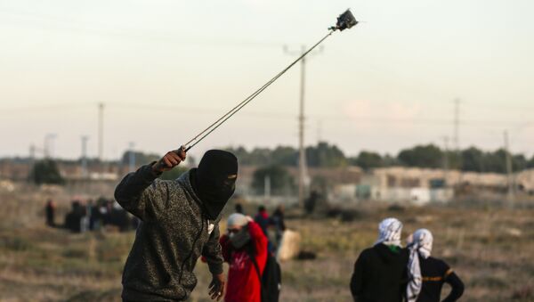 A Palestinian protester hurls a rock at Israeli forces during clashes near the Israel-Gaza border east of Gaza City on December 9, 2017 - Sputnik International