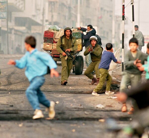 Palestinian youngsters flee Israeli soldiers during riots 26 November 1993 in Gaza City Palestinian youngsters flee Israeli soldiers during riots 26 November 1993 in Gaza City - Sputnik International