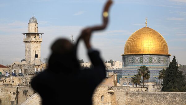 A man is silhouetted while he blows a Shofar, a ram horn, as the Dome of the Rock (R), located in Jerusalem's Old City on the compound known to Muslims as Noble Sanctuary and to Jews as Temple Mount, is seen in the background December 10, 2017 - Sputnik International