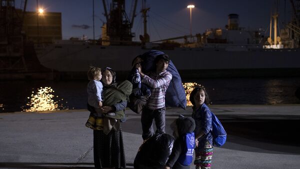 An Afghan family stand with their belongings after their arrival on a Greek ferry, at the port of Piraeus near Athens, early Wednesday, Dec. 13, 2017 - Sputnik International