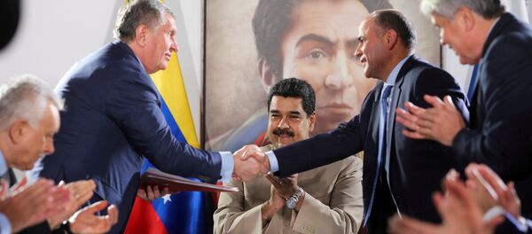 Head of Russian state oil firm Rosneft Igor Sechin (standing L) shakes hands with Venezuela's Oil Minister and President of the Venezuelan state oil company PDVSA Manuel Quevedo, in front of Venezuela's President Nicolas Maduro, in Maiquetia, Venezuela December 16, 2017. - Sputnik International
