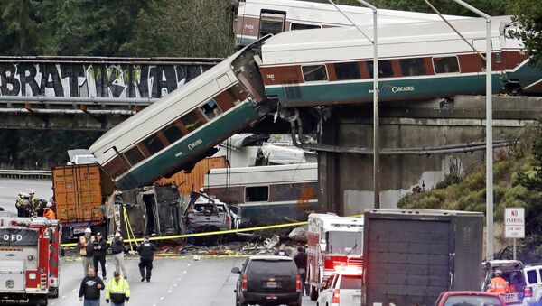 Cars from an Amtrak train lay spilled onto Interstate 5 below alongside smashed vehicles as some train cars remain on the tracks above Monday, Dec. 18, 2017, in DuPont, Wash. The Amtrak train making the first-ever run along a faster new route hurtled off the overpass Monday near Tacoma and spilled some of its cars onto the highway below, killing some people, authorities said. Seventy-eight passengers and five crew members were aboard when the train moving at more than 80 mph derailed about 40 miles south of Seattle before 8 a.m., Amtrak said. - Sputnik International