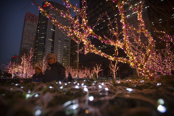 People walk past a display of Christmas lights outside a building in the central business district of Beijing - Sputnik International