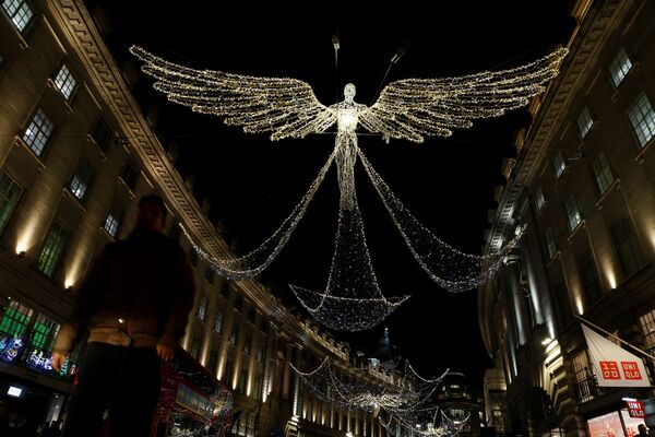 A man walks beneath Christmas street lights on Regent Street in London, Britain - Sputnik International