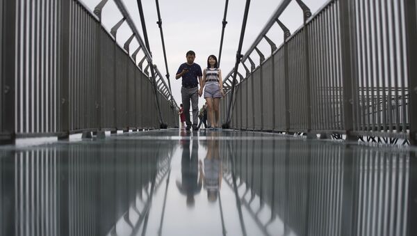 (File) In this photo taken on June 1, 2017, a couple walks on a glass-bottomed skywalk, certified as the world's longest, at the Ordovician park in Wansheng - Sputnik International