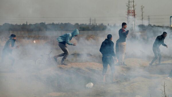Palestinian demonstrators react to tear gas fired by Israeli troops during clashes at a protest as Palestinians call for a Day of Rage in response to U.S. President Donald Trump's recognition of Jerusalem as Israel's capital, near the border with Israel in the east of Gaza City, December 22, 2017 - Sputnik International