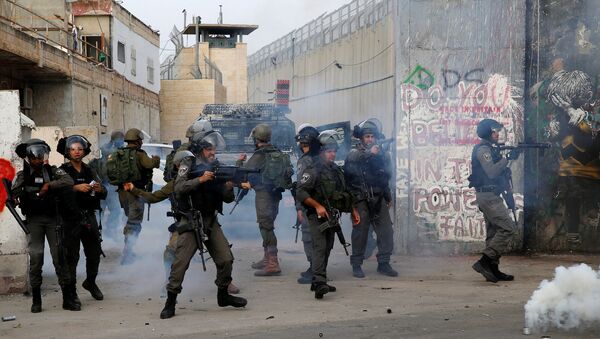 An Israeli border policeman fires tear gas canisters at Palestinian demonstrators during clashes in the West Bank city of Bethlehem, December 23, 2017 - Sputnik International