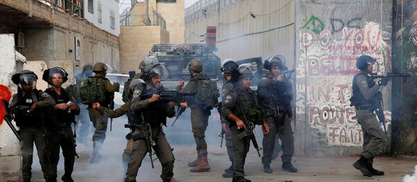 An Israeli border policeman fires tear gas canisters at Palestinian demonstrators during clashes in the West Bank city of Bethlehem, December 23, 2017 An Israeli border policeman fires tear gas canisters at Palestinian demonstrators during clashes in the West Bank city of Bethlehem, December 23, 2017 - Sputnik International