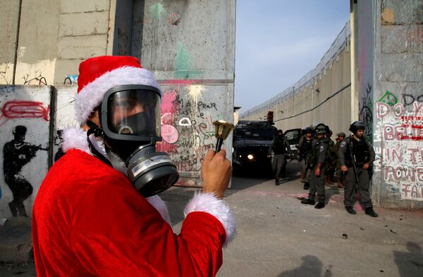 A Palestinian dressed as Santa Claus stands in front of Israeli troops during a protest in the West Bank city of Bethlehem, December 23, 2017 - Sputnik International
