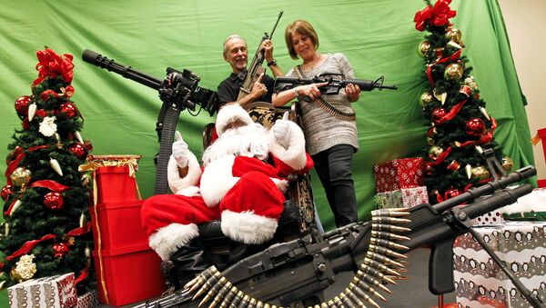 Ron Ingram and Barbara Ingram, right, pose with Santa for a photograph at the third annual Santa and Machine Guns event at the Scottsdale Gun Club Dec. 2, 2012, in Scottsdale, Ariz. - Sputnik International