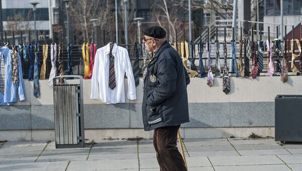 A man passes by hundreds of collected ties and shirts hanging on the fence of the government building on Tuesday, Dec. 26, 2017, in Kosovo capital Pristina - Sputnik International