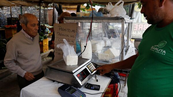 A vendor weighs cheese for a customer at a street market in Caracas, Venezuela December 19, 2017. Picture taken December 19, 2017. - Sputnik International