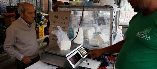 A vendor weighs cheese for a customer at a street market in Caracas, Venezuela December 19, 2017. Picture taken December 19, 2017. A vendor weighs cheese for a customer at a street market in Caracas, Venezuela December 19, 2017. Picture taken December 19, 2017. - Sputnik International