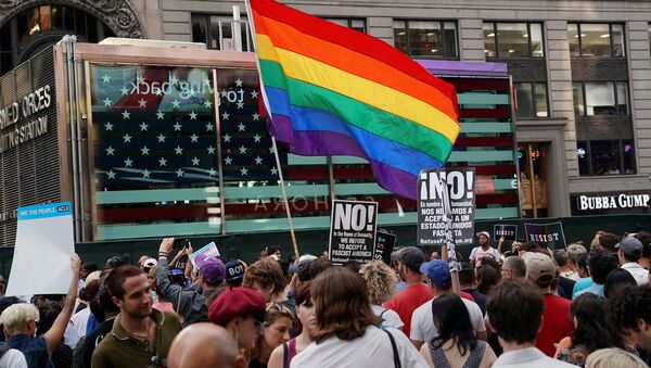 A rainbow flag flies as people protest U.S. President Donald Trump's announcement that he plans to reinstate a ban on transgender individuals from serving in any capacity in the U.S. military, in Times Square, in New York City, New York, U.S., July 26, 2017. - Sputnik International