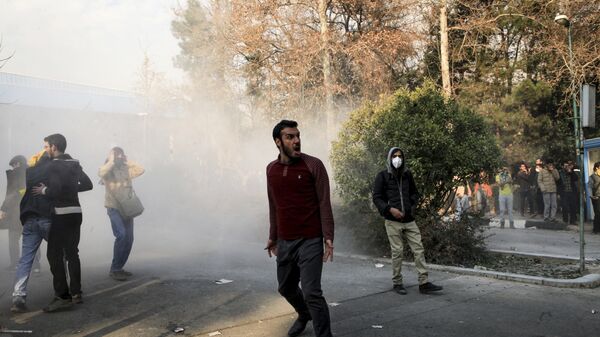 Iran, university students attend a protest inside Tehran University while a smoke grenade is thrown by anti-riot Iranian police, in Tehran, Iran, Saturday, Dec. 30, 2017 - Sputnik International