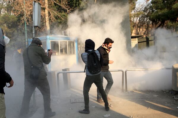 Iranian students run for cover from tear gas at the University of Tehran during a demonstration driven by anger over economic problems, in the capital Tehran on December 30, 2017 Iranian students run for cover from tear gas at the University of Tehran during a demonstration driven by anger over economic problems, in the capital Tehran on December 30, 2017 - Sputnik International