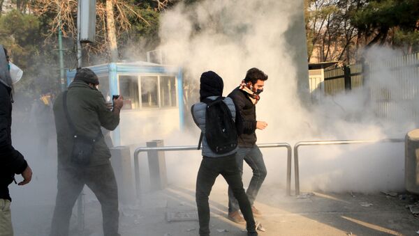 Iranian students run for cover from tear gas at the University of Tehran during a demonstration driven by anger over economic problems, in the capital Tehran on December 30, 2017 - Sputnik International