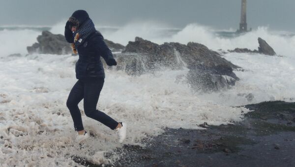 A woman runs as waves crash against the seafront in Auderville, Normandy, as storm Eleanor hits the northern part of France on January 3, 2018 - Sputnik International
