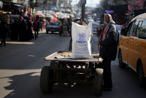 A Palestinian man stands next to a cart carrying a flour sack distributed by the United Nations Relief and Works Agency (UNRWA) in Khan Younis refugee camp in the southern Gaza Strip January 3, 2018 A Palestinian man stands next to a cart carrying a flour sack distributed by the United Nations Relief and Works Agency (UNRWA) in Khan Younis refugee camp in the southern Gaza Strip January 3, 2018 - Sputnik International