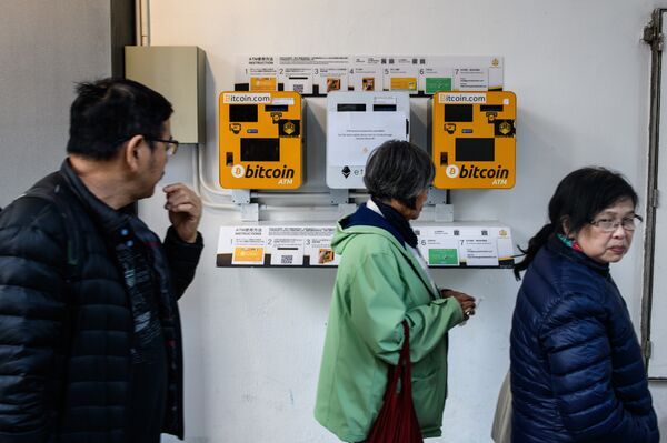 Pedestrians walk past ATM machines (L and R) for digital currency Bitcoin in Hong Kong on December 18, 2017 - Sputnik International