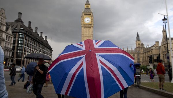 A pedestrian shelters from the rain beneath a Union flag themed umbrella as they walk near the Big Ben clock face and the Elizabeth Tower at the Houses of Parliament in central London. (File) - Sputnik International