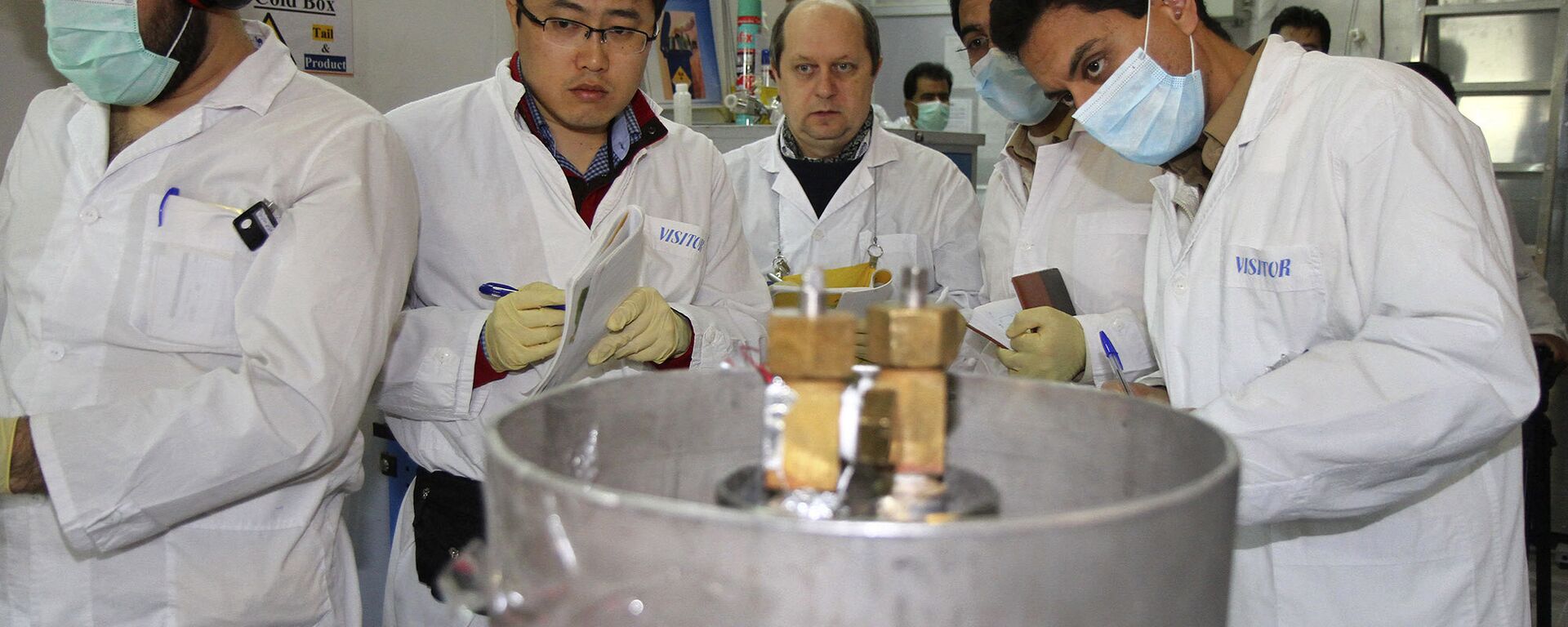 Unidentified International Atomic Energy Agency (IAEA) inspectors and Iranian technicians are on hand to cut the connections between the twin cascades for 20 percent uranium enrichment at Natanz facility, some 200 miles (322 kilometers) south of the capital Tehran, Iran, Monday, Jan. 20, 2014 - Sputnik International, 1920, 04.09.2019