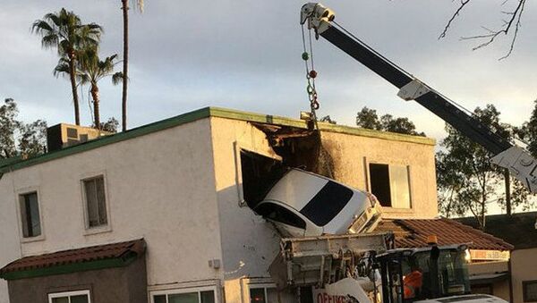 Rescue workers remove a car that crashed into a building after speeding into a median and going airborne, according to local media, in Santa Ana, California, U.S., January 14, 2018, in this picture obtained from social media - Sputnik International