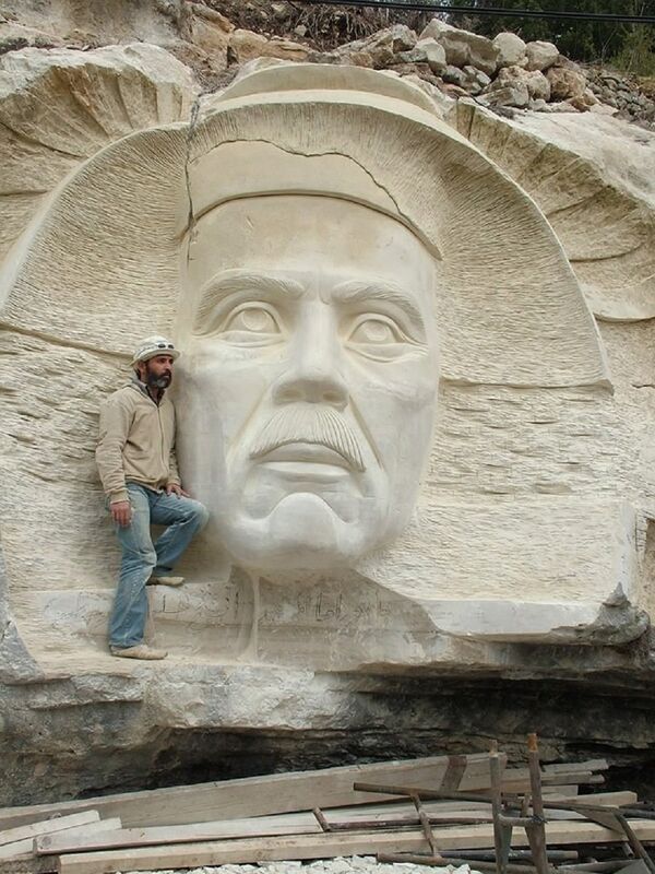 Syrian sculptor Alaa Ali Muhammed is seen standing near the bas-relief he created in Tartus province Syrian sculptor Alaa Ali Muhammed is seen standing near the bas-relief he created in Tartus province - Sputnik International