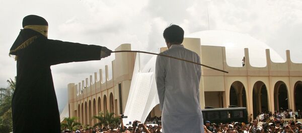 A Sharia law official whips a man , Aceh province, Indonesia (File) A Sharia law official whips a man , Aceh province, Indonesia (File) - Sputnik International