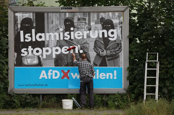 A man sticks an Alternative for Germany (AfD)'s electoral poster reading stop islamization in Berlin on September 7, 2017 - Sputnik International