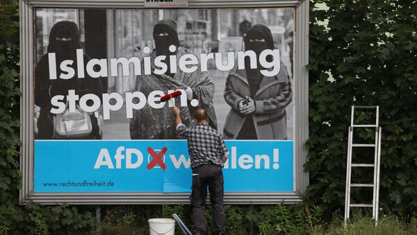 A man sticks an Alternative for Germany (AfD)'s electoral poster reading stop islamization in Berlin on September 7, 2017 - Sputnik International