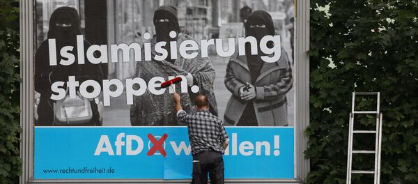 A man sticks an Alternative for Germany (AfD)'s electoral poster reading stop islamization in Berlin on September 7, 2017 - Sputnik International