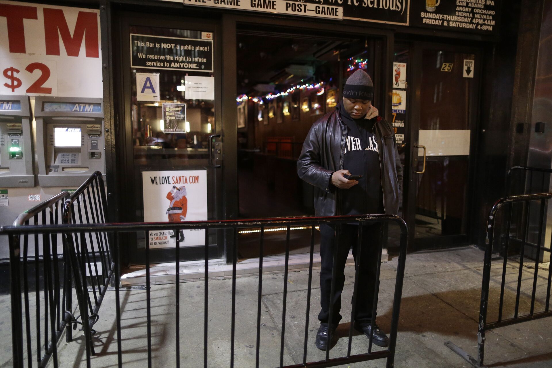In this Wednesday, Dec. 9, 2015, photo a bouncer stands next to a sign professing love for Santacon hanging in the window of the Continental bar in New York - Sputnik International, 1920, 12.05.2022