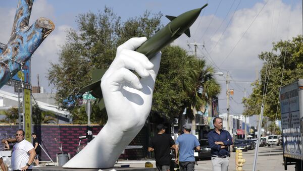 A sculpture titled Dangerous Game by Italian artist Lorenzo Quinn, right, is displayed in the Wynwood neighborhood of Miami, Friday, Dec. 8, 2017. The two-part installation shows a giant hand holding a nuclear missile as if it were a dart - Sputnik International