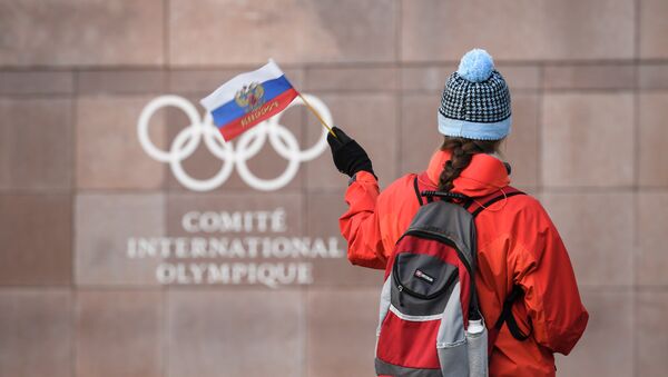 A supporter waves a Russian flag in front of the logo of the International Olympic Committee (IOC) at their headquarters on December 5, 2017 in Pully near Lausanne - Sputnik International