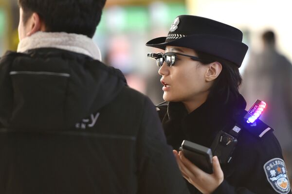 Police officer (R) speaking as she wears a pair of smartglasses with a facial recognition system at Zhengzhou East Railway Station in Zhengzhou in China's central Henan province. File photo  - Sputnik International