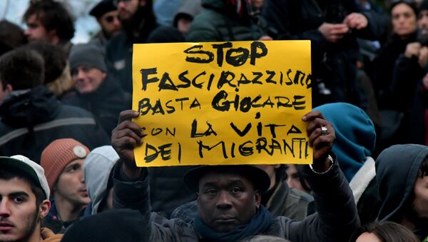 A protester holds a placard reading stop to the fascism and racism, stop playing with the migrants' life during an anti-racism demonstration one week after an attack that injured at least six migrants, on February 10, 2018 in Macerata - Sputnik International