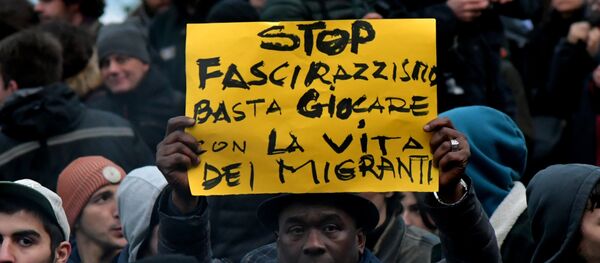A protester holds a placard reading stop to the fascism and racism, stop playing with the migrants' life during an anti-racism demonstration one week after an attack that injured at least six migrants, on February 10, 2018 in Macerata A protester holds a placard reading stop to the fascism and racism, stop playing with the migrants' life during an anti-racism demonstration one week after an attack that injured at least six migrants, on February 10, 2018 in Macerata - Sputnik International