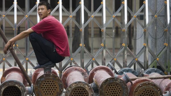 A Chinese man pause as he waits for steel pipes to be loaded onto a truck in Beijing, China. (File) - Sputnik International