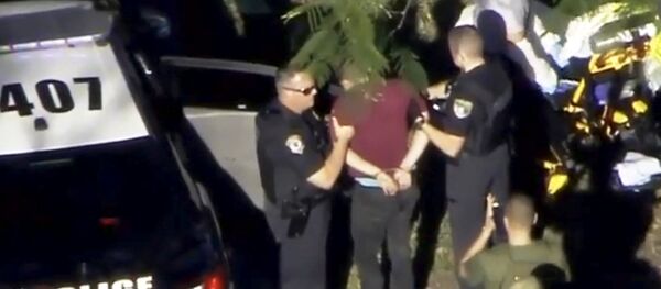 A man placed in handcuffs is led by police near Marjory Stoneman Douglas High School following a shooting incident in Parkland, Florida, U.S. February 14, 2018 in a still image from video - Sputnik International